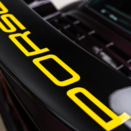 Černá automobilová mřížka s velkým žlutým označením na povrchu