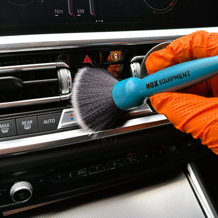 Dvojitý štětec DualBrush v oranžových rukavicích čistí palubní desku černým štětcem