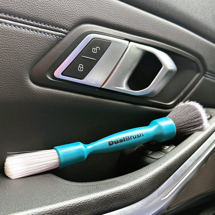 Dvojitý štětec DualBrush na plastu dveří: tyrkysová rukojeť s bílými štětinami