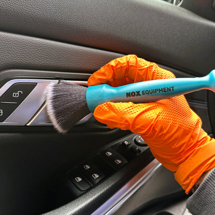 Dvojitý štětec DualBrush v oranžových rukavicích čistí ovládací panel černým štětcem
