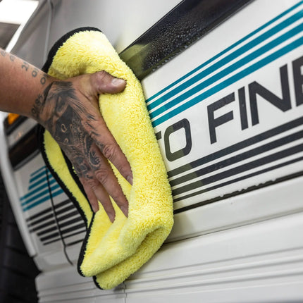 Mikrovláknový sušící ručník Auto Finesse Primo, žlutý s černým lemem, přeložený v dlani