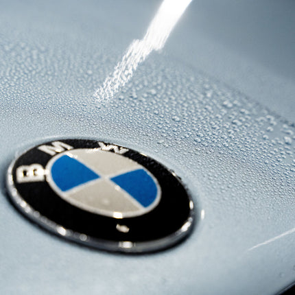 Logo BMW na kapotě s pěnou a kapkami