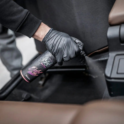 Stříkací lahev Odor Killer u autosedačky, aplikace na černý povrch
