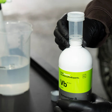 Přípravek Koch Chemie Vorreiniger B v bílé lahvi s víčkem, drží v rukavici